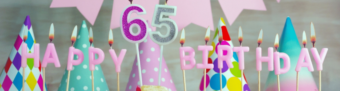 Seniors celebrating a 65 birthday party with cake and party hats.