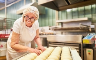 Senior woman working in a bakery, representing seniors working past 65 and considering Medicare enrollment.