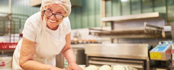 Senior woman working in a bakery, representing seniors working past 65 and considering Medicare enrollment.